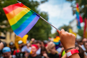 A crowd of people hold rainbow flags, representing the support a LGBTQ therapist can offer from the comfort of home via online LGBTQ therapy in Kent County, MI. Learn more about LGBTQ therapy in Kent County, MI by searching "LGBTQ therapist in Kent County, MI" today.