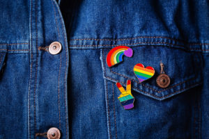 A close up of rainbow pins on a jean jacket, representing the support LGBTQ therapy in Grand Rapids, MI can offer. Learn more about online LGBTQ therapy in Kent County, MI by contacting an LGBTQ therapist in Grand Rapids, MI or search "LGBTQ therapist in Kent County, MI" today.