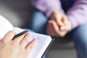 A close up of a person with a clipboard while another person sits across from them. Learn more about EMDR therapy in Grand Rapids, MI and the support an EMDR therapist in Grand Rapids, MI can offer. We offer online EMDR therapy in Kent County, MI and more