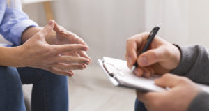A close up of a person taking notes on a clipboard and listening to the person near them. This could represent how couples therapy in Grand Rapids, MI can help you address relationship issues. Learn more about couples therapy in Kent County, MI and other services by contacting a couples therapist in Grand Rapids, MI today.
