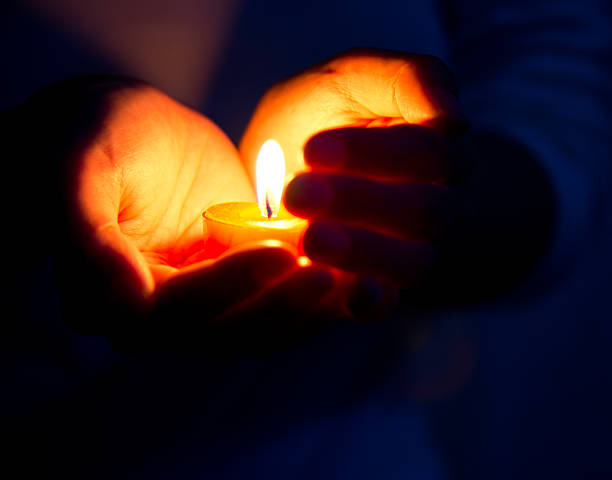 A close up of a person holding a candle, symmbolizing the support a grief counselor in Grand Rapids, MI can offer. Learn more about counseling for grief in Grand Rapids, MI by searching online grief counseling in Kent County, MI today.