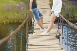 Two people stand on a wooden bridge as they talk. An online therapist in Michigan can offer communication support from the support of home. Learn about online therapy in Michigan by contacting a couples therapist in Grand Rapids, MI today.