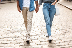 A couple hold hands as they walk with one another down a street. This symbolizes the bond created after coupes therapy in Kent County, MI. Learn more about couples therapy and marriage counseling in Kent County, MI by contacting a couples therapist in Grand Rapids, MI today.