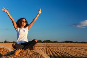Teen outside with her hands in the air representing the happiness she feels after going to teenage counseling in Kent County, Michigan. Online Therapy in MI is available now, reach out today! 